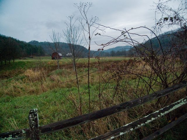 A field and a fence, a red barn far off